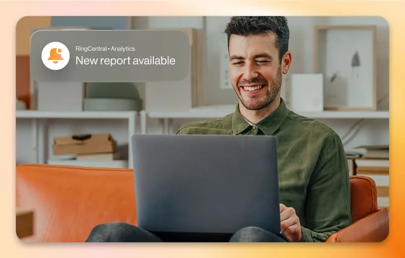 An inlay of a RingCentral Analytics notification that says New Report Available on top of a man holding his laptop while sitting on a couch